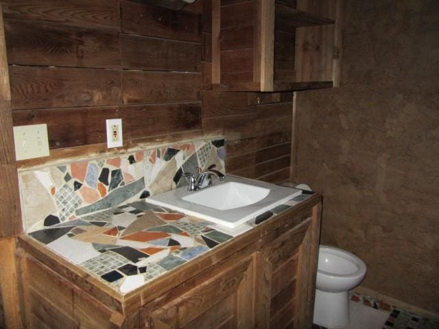 bathroom featuring vanity, toilet, and backsplash