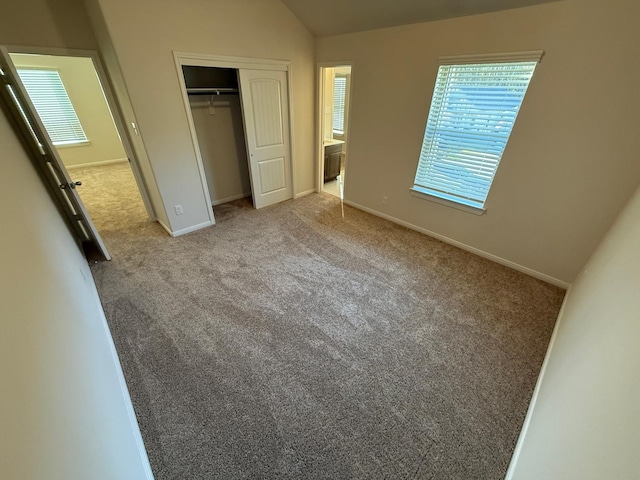 unfurnished bedroom with light colored carpet, lofted ceiling, and a closet