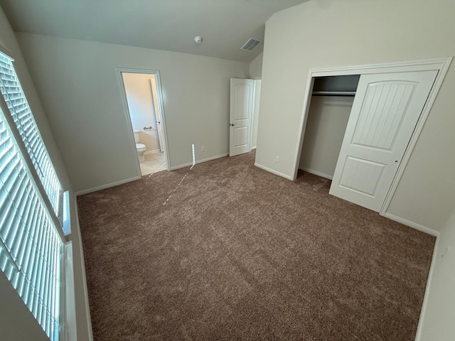 unfurnished bedroom with carpet flooring, ensuite bath, a closet, and vaulted ceiling