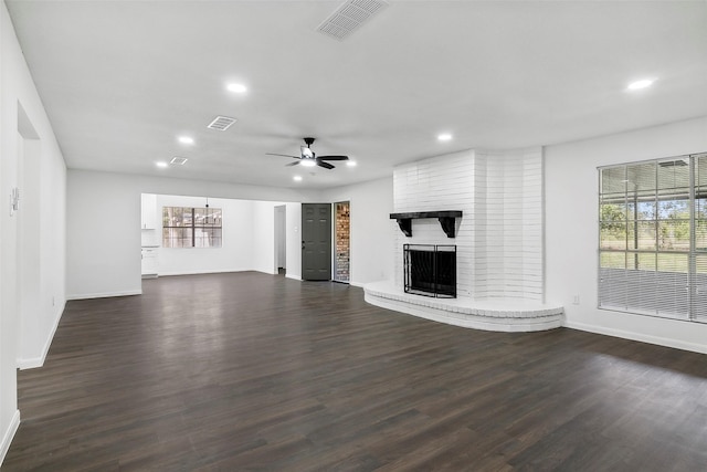 unfurnished living room with ceiling fan, a fireplace, and dark wood-type flooring