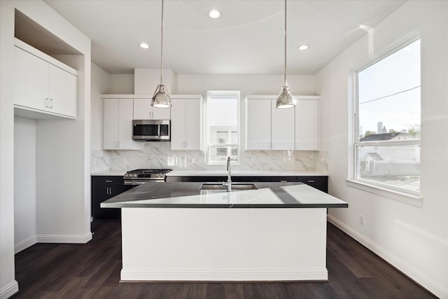 kitchen with hanging light fixtures, appliances with stainless steel finishes, and a kitchen island with sink