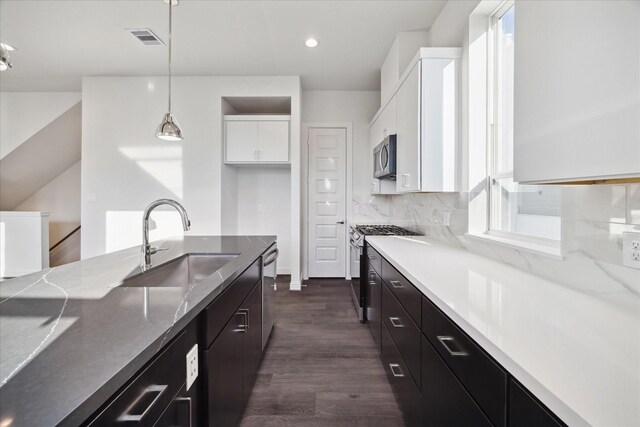 kitchen featuring white cabinets, sink, hanging light fixtures, and stainless steel appliances