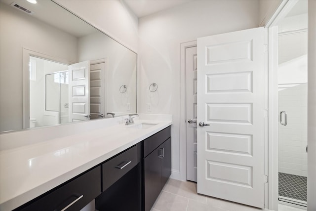 bathroom featuring tile patterned flooring, vanity, toilet, and walk in shower