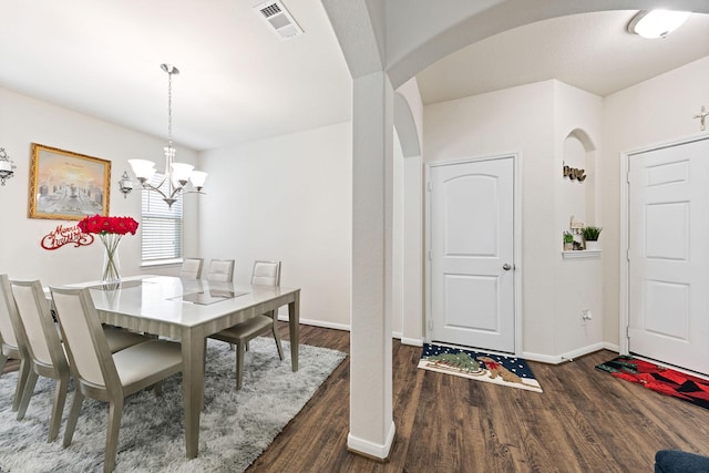 dining area with dark wood-type flooring and a notable chandelier