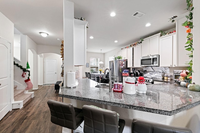 kitchen featuring white cabinets, kitchen peninsula, appliances with stainless steel finishes, and a kitchen bar