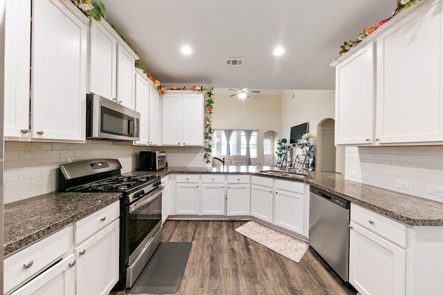 kitchen featuring sink, dark stone countertops, appliances with stainless steel finishes, kitchen peninsula, and white cabinets