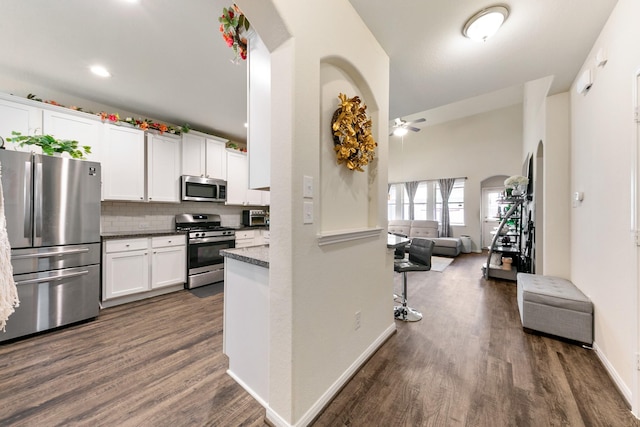 kitchen featuring dark hardwood / wood-style floors, white cabinets, backsplash, dark stone counters, and stainless steel appliances