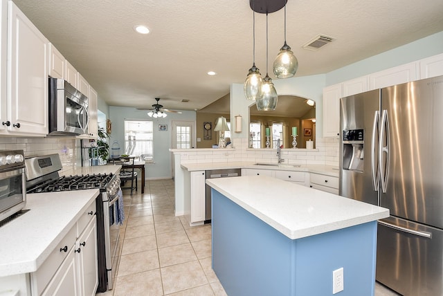 kitchen with white cabinetry, stainless steel appliances, a kitchen island, and kitchen peninsula