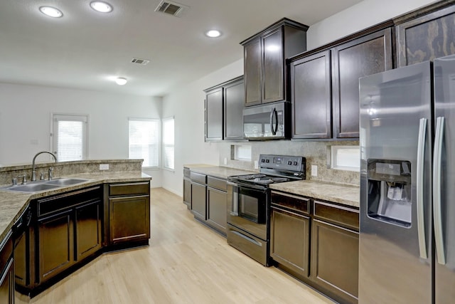 kitchen with dark brown cabinets, stainless steel appliances, light hardwood / wood-style floors, and sink