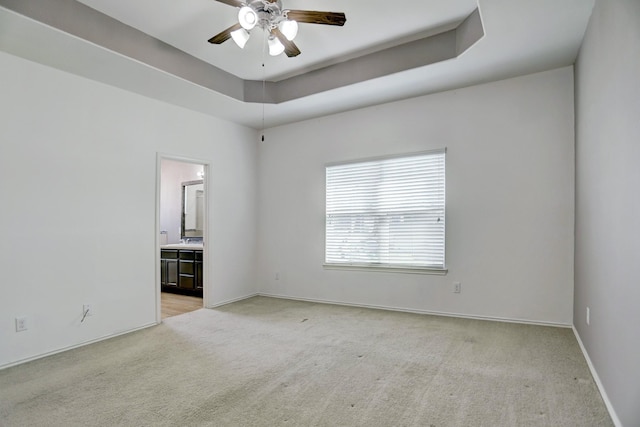 carpeted empty room featuring a tray ceiling and ceiling fan