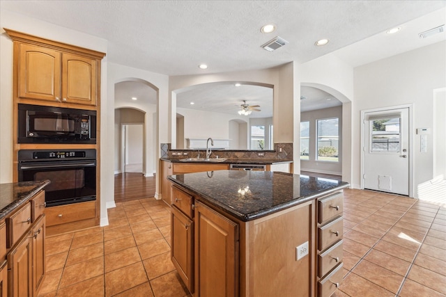 kitchen featuring light tile patterned flooring, sink, a center island, ceiling fan, and black appliances