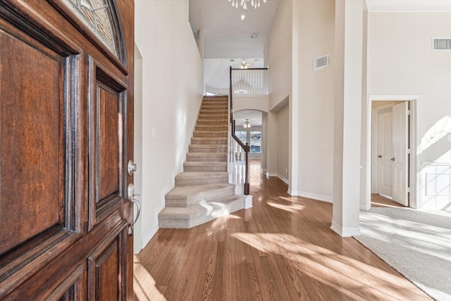 foyer with hardwood / wood-style floors, a towering ceiling, and ceiling fan