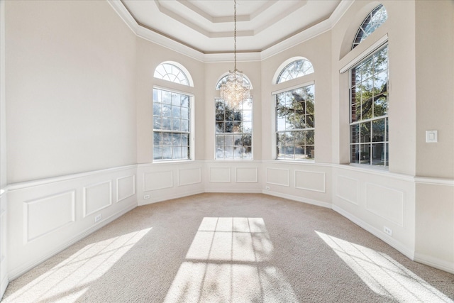 interior space featuring an inviting chandelier, a healthy amount of sunlight, a tray ceiling, and light carpet