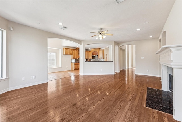 unfurnished living room with hardwood / wood-style flooring, a tile fireplace, and ceiling fan