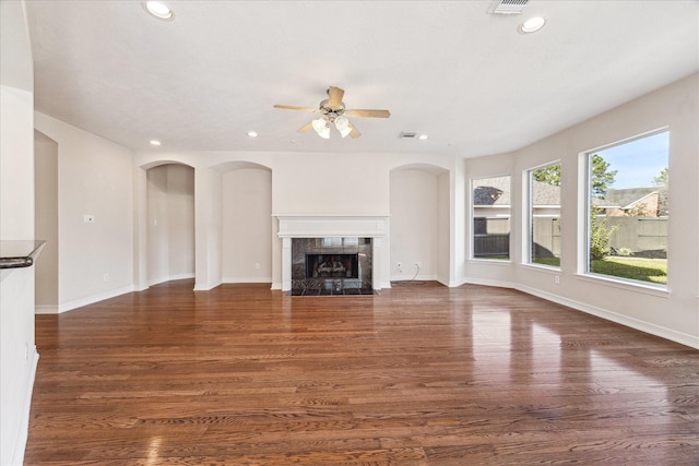 unfurnished living room featuring ceiling fan, a fireplace, and dark hardwood / wood-style floors