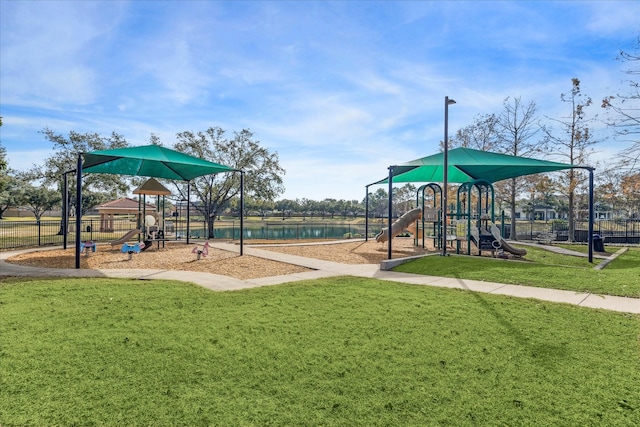 view of playground featuring a lawn and a water view