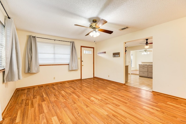 unfurnished room featuring light hardwood / wood-style floors and a textured ceiling