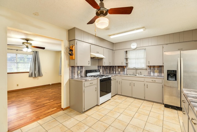 kitchen featuring gas range, a textured ceiling, stainless steel fridge, and decorative backsplash