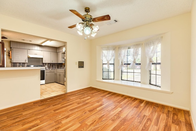 unfurnished living room featuring ceiling fan, a textured ceiling, and light hardwood / wood-style floors