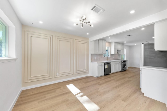 kitchen with decorative backsplash, appliances with stainless steel finishes, light hardwood / wood-style floors, white cabinets, and a chandelier