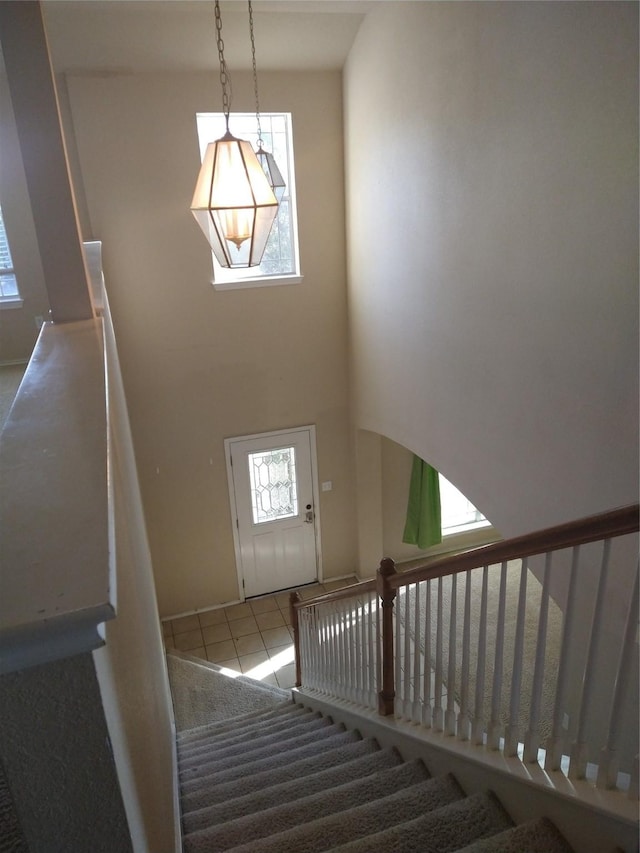 stairway with plenty of natural light and tile patterned flooring