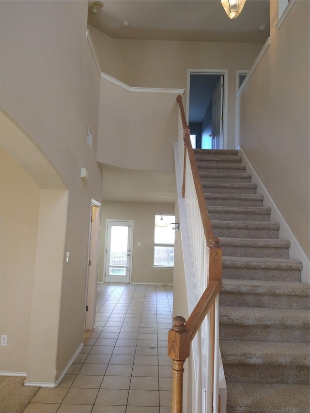 stairway with tile patterned flooring and a high ceiling