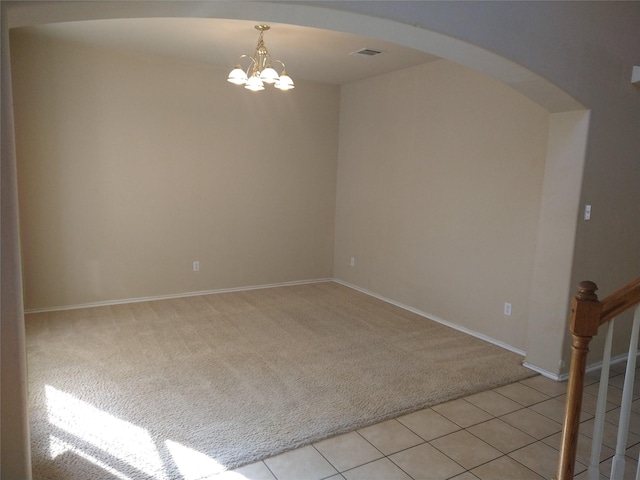 carpeted empty room with an inviting chandelier