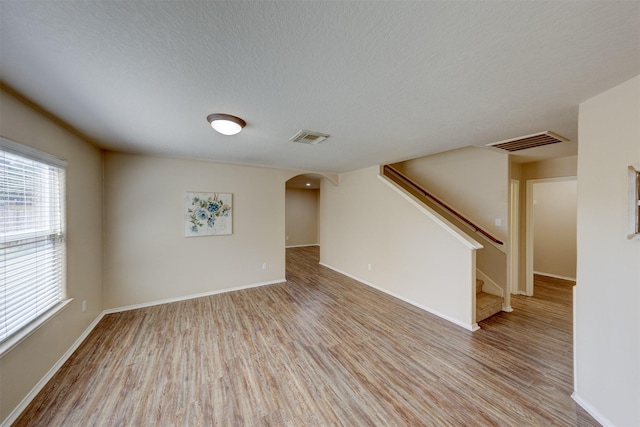 spare room featuring light hardwood / wood-style floors and a textured ceiling