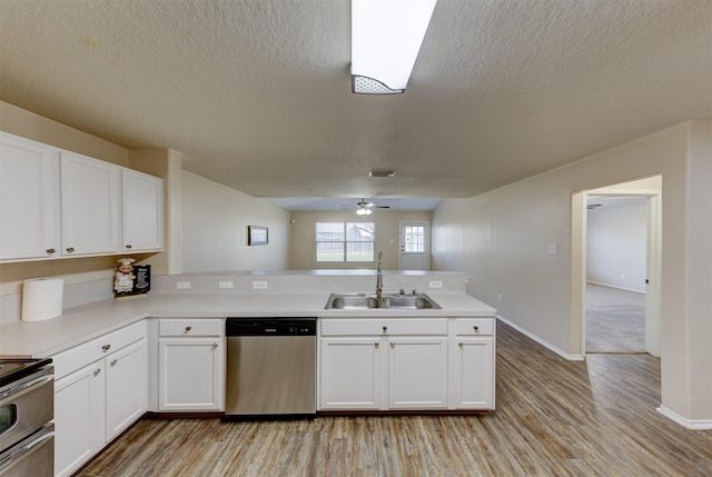 kitchen with kitchen peninsula, stainless steel appliances, white cabinets, and sink