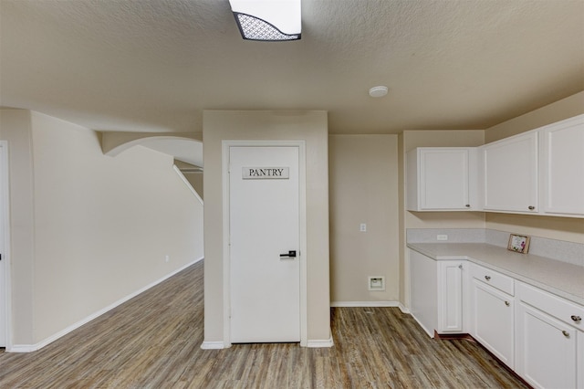 kitchen featuring white cabinetry, a textured ceiling, and light wood-type flooring