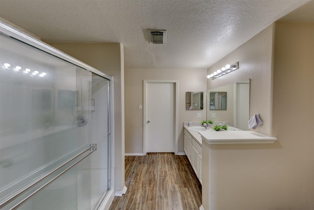 bathroom featuring vanity, a textured ceiling, hardwood / wood-style flooring, and walk in shower