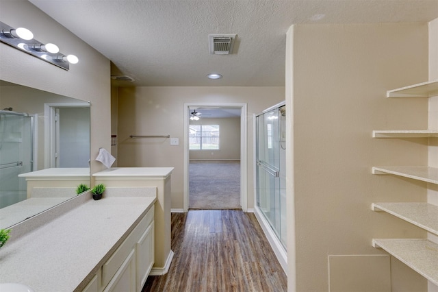 bathroom featuring vanity, a textured ceiling, a shower with door, ceiling fan, and wood-type flooring