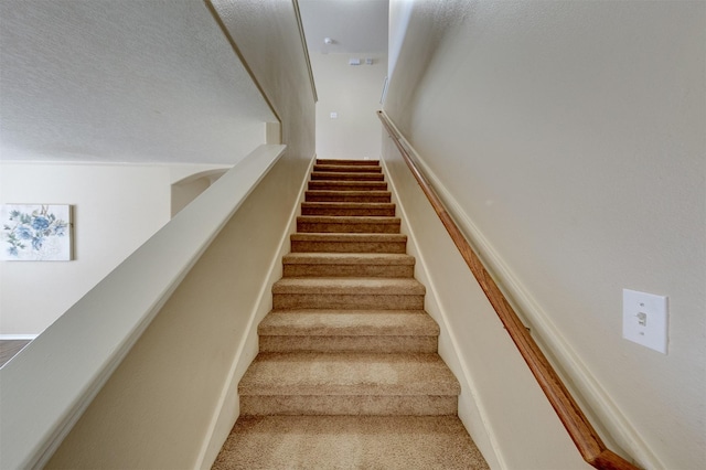 staircase featuring a textured ceiling