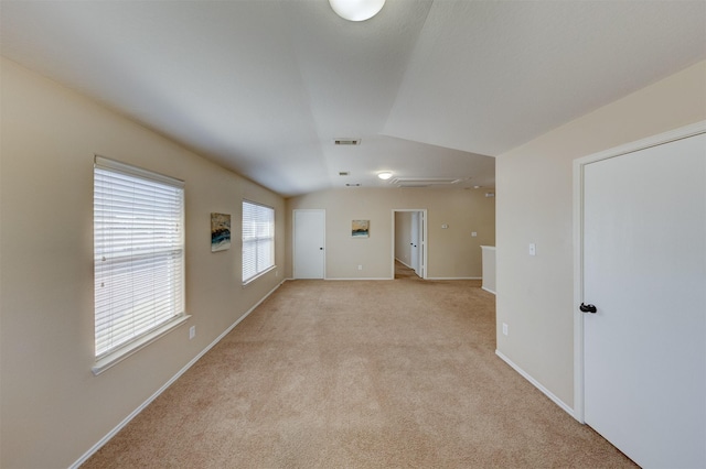 carpeted spare room featuring vaulted ceiling