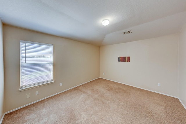 carpeted empty room featuring a textured ceiling and vaulted ceiling