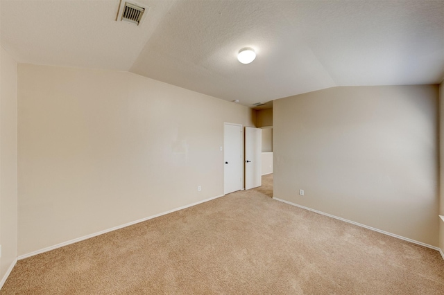 carpeted spare room featuring lofted ceiling and a textured ceiling