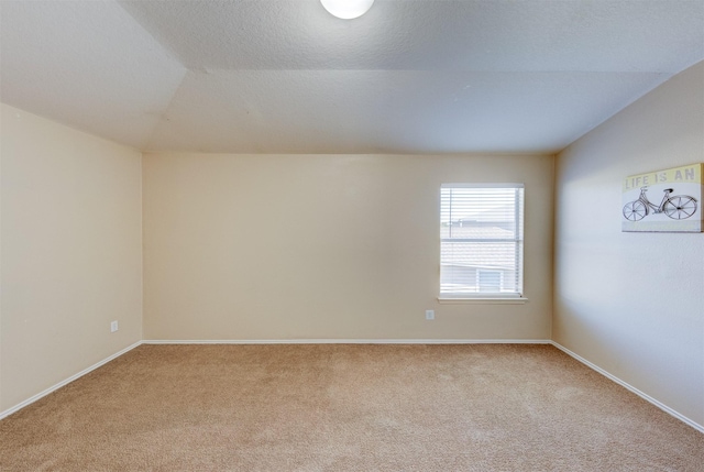 carpeted empty room featuring a textured ceiling and vaulted ceiling