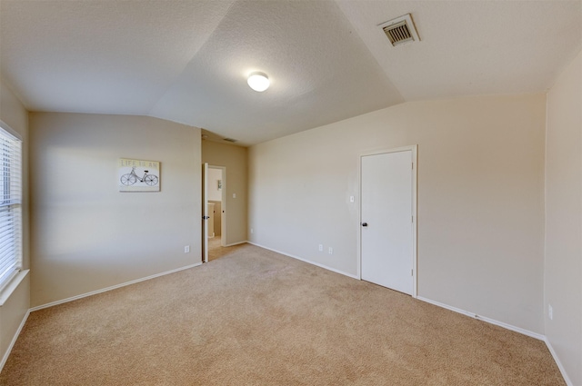 carpeted spare room featuring vaulted ceiling and a textured ceiling