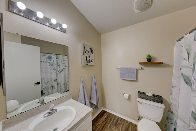 bathroom with vanity, a textured ceiling, vaulted ceiling, wood-type flooring, and toilet