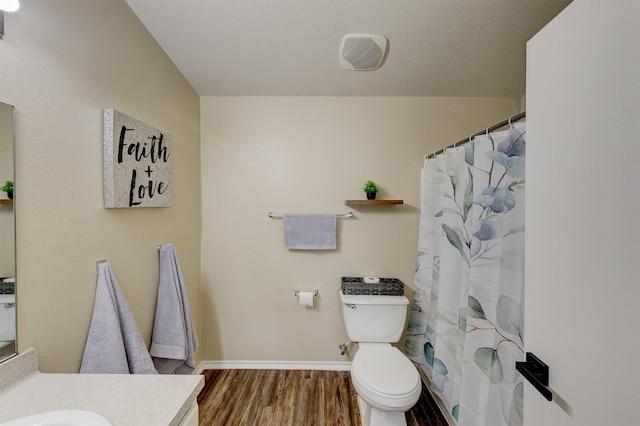 bathroom featuring vanity, wood-type flooring, a textured ceiling, and toilet