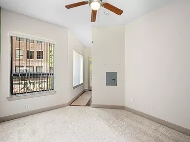 spare room featuring ceiling fan, electric panel, and carpet flooring