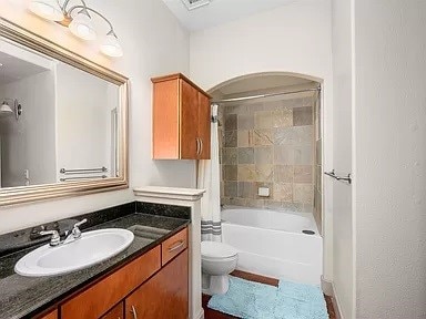 full bathroom with toilet, vanity, and tiled shower / bath