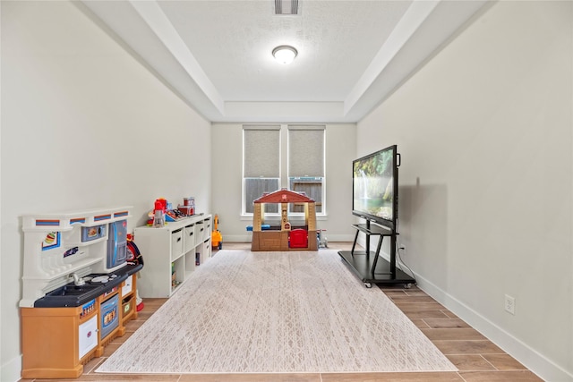 playroom with a raised ceiling and a textured ceiling