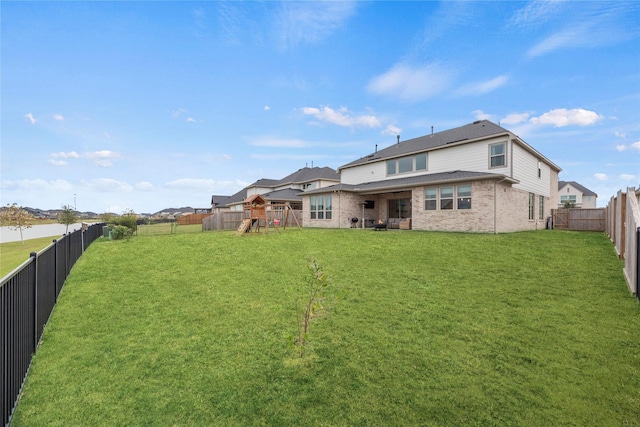 rear view of house featuring a playground and a yard