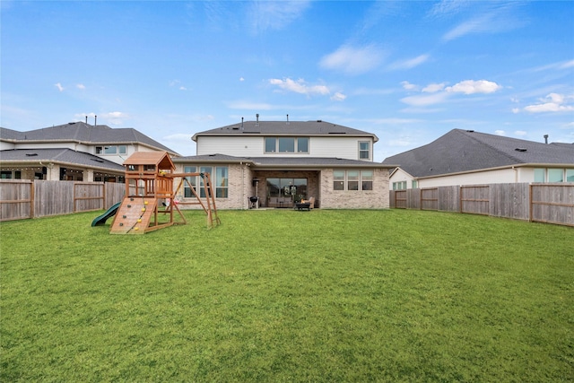 back of house with a yard and a playground