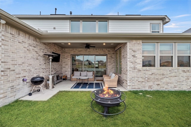 back of property with a lawn, a patio area, ceiling fan, and an outdoor living space with a fire pit