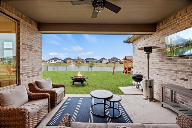 view of patio / terrace featuring a playground, grilling area, ceiling fan, and an outdoor living space with a fire pit