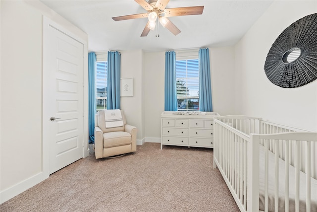 bedroom featuring ceiling fan, light colored carpet, and a crib