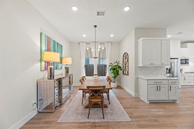 dining area with light hardwood / wood-style floors and a notable chandelier