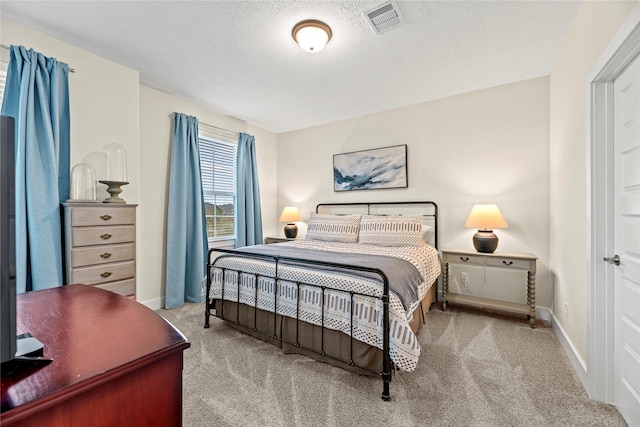 bedroom with light carpet and a textured ceiling